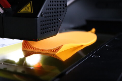 Ein 3D-Drucker fertigt die ergonomische Support-Struktur einer personalisierten orangefarbenen Einlage von Laufgsund f&uuml;r pr&auml;ventiven Halt und Stabilit&auml;t.